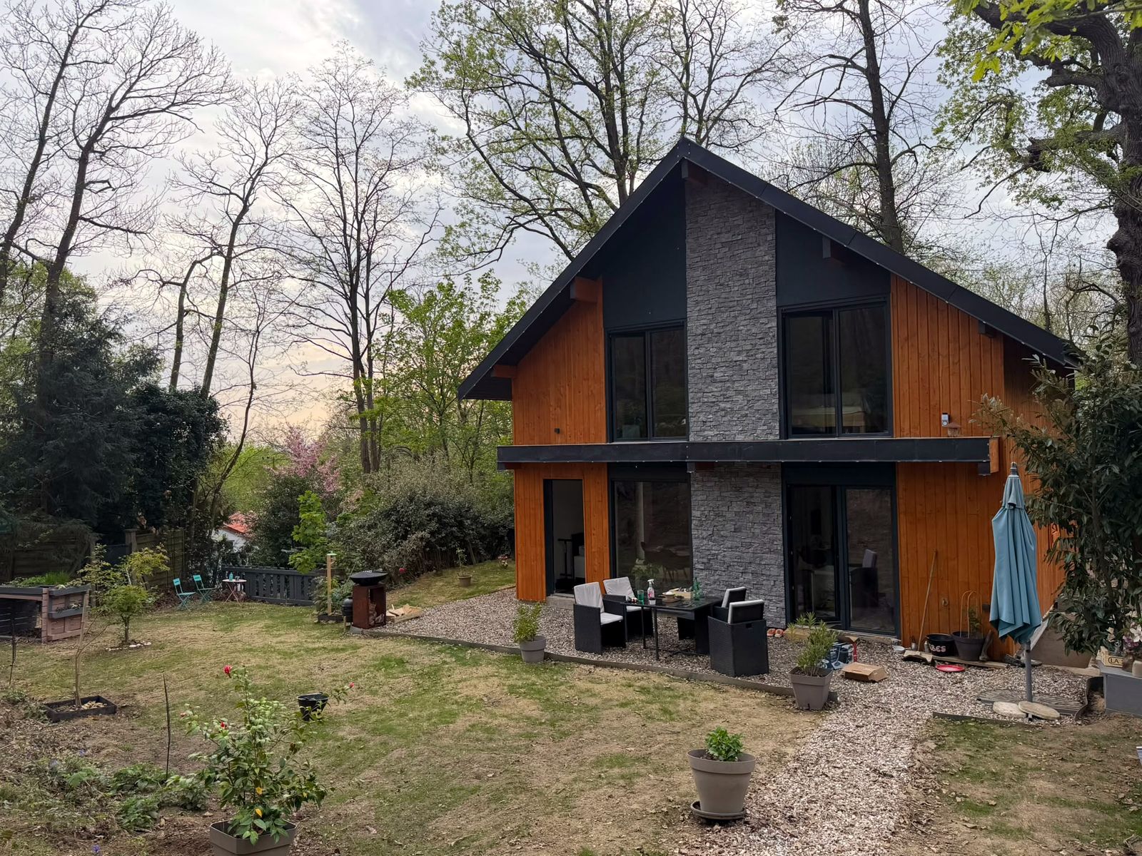 Vivienda contemporánea con revestimiento de madera y piedra, construida por Design Probat